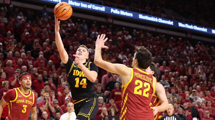 Dec 11, 2025; Ames, Iowa, USA;  Iowa Hawkeyes guard Bennett Stirtz (14) scores over Iowa State Cyclones forward Milan Momcilovic (22) during the second half at James H. Hilton Coliseum. Mandatory Credit: Reese Strickland-Imagn Images