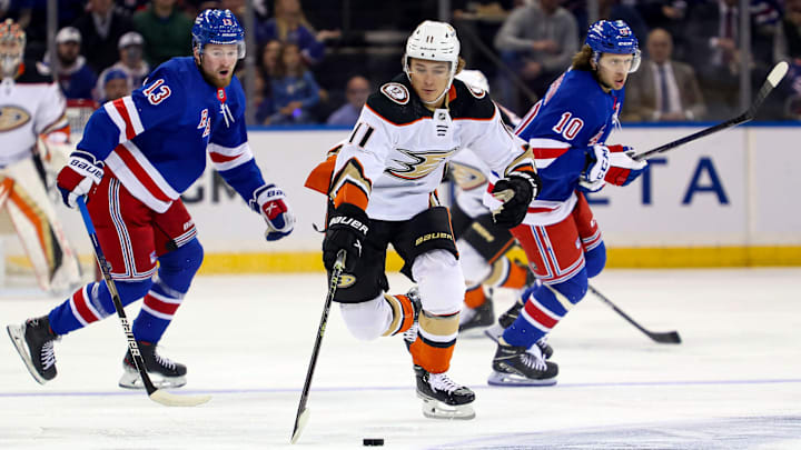 Oct 17, 2022; New York, New York, USA; Anaheim Ducks center Trevor Zegras (11) reaches for the puck in front of New York Rangers left wing Alexis Lafreniere (13) and New York Rangers left wing Artemi Panarin (10) during the first period at Madison Square Garden. Mandatory Credit: Danny Wild-Imagn Images