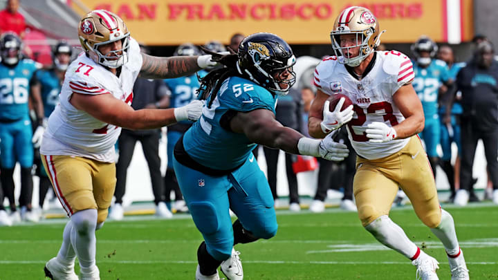 Sep 28, 2025; Santa Clara, California, USA; San Francisco 49ers running back Christian McCaffrey (23) runs the ball as Jacksonville Jaguars defensive tackle DaVon Hamilton (52) defends during the second half at Levi's Stadium. Mandatory Credit: Darren Yamashita-Imagn Images