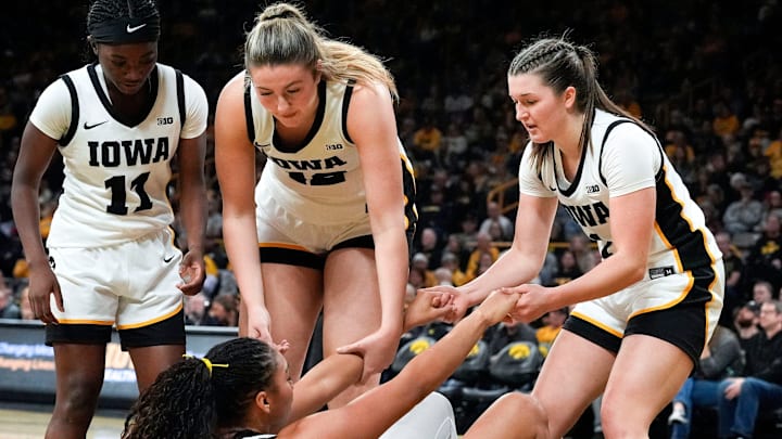 Iowa guard Chit-Chat Wright (11), Iowa center Layla Hays (12), and Iowa guard Taylor Stremlow (1) help up Iowa forward Hannah Stuelke (45) Dec. 28, 2025 at Carver-Hawkeye Arena in Iowa City, Iowa.