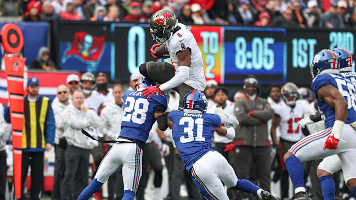 Nov 24, 2024; East Rutherford, New Jersey, USA; Tampa Bay Buccaneers running back Rachaad White (1) fights for yards over New York Giants cornerback Cor'Dale Flott (28) and safety Tyler Nubin (31) during the first half at MetLife Stadium. Mandatory Credit: Vincent Carchietta-Imagn Images