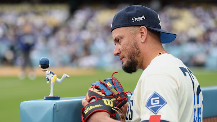 Apr 25, 2026; Los Angeles, California, USA; Los Angeles Dodgers infielder Miguel Rojas (72) looks at a bobblehead depicting pitcher Roki Sasaki (not pictured) before the game against the Chicago Cubs at Dodger Stadium. Mandatory Credit: Kiyoshi Mio-Imagn Images