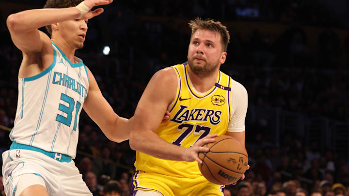 Feb 19, 2025; Los Angeles, California, USA: Los Angeles Lakers guard Luka Doncic (77) drives against Charlotte Hornets forward Tidjane Salaun (31) during the second quarter at Crypto.com Arena. Mandatory Credit: Jason Parkhurst-Imagn Images