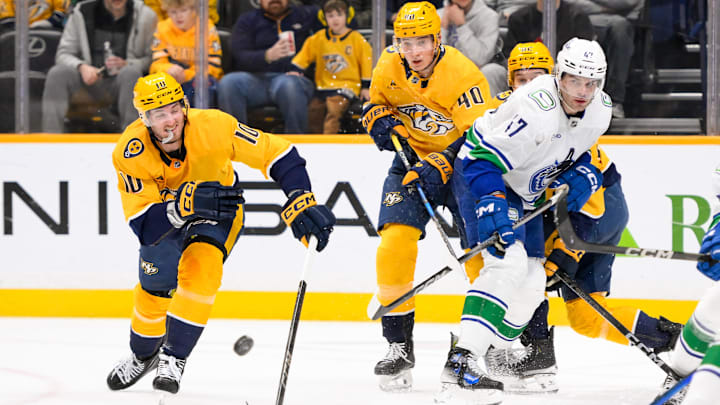 Jan 29, 2025; Nashville, Tennessee, USA;  Nashville Predators center Colton Sissons (10) and Vancouver Canucks defenseman Noah Juulsen (47) battle for the puck during the third period at Bridgestone Arena. Mandatory Credit: Steve Roberts-Imagn Images