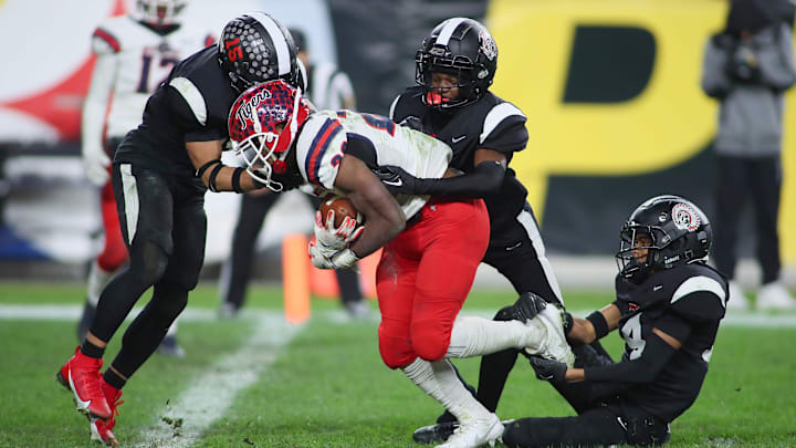 Aliquippa's QaLil Goode (14), Gavin Wilcox (13), and Arison Walker (15) attempt to hold back McKeesport's Kemon Spell (20) from scoring a touchdown during the second half of the WPIAL 4A Championship game Friday evening at Acrisure Stadium in Pittsburgh, PA.