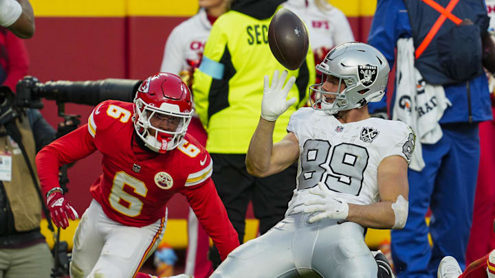 Nov 29, 2024; Kansas City, Missouri, USA; Las Vegas Raiders tight end Brock Bowers (89) tosses the ball after scoring a touchdown against Kansas City Chiefs safety Bryan Cook (6) during the second half at GEHA Field at Arrowhead Stadium. Mandatory Credit: Jay Biggerstaff-Imagn Images
