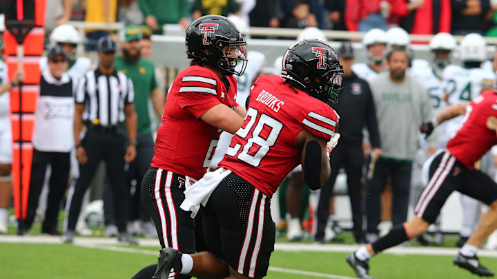 Oct 19, 2024; Lubbock, Texas, USA;  Texas Tech Red Raiders quarterback Behren Morton (2) hands the ball to running back Tahj Brooks (28) against the Baylor Bears in the first half at Jones AT&T Stadium and Cody Campbell Field. Mandatory Credit: Michael C. Johnson-Imagn Images