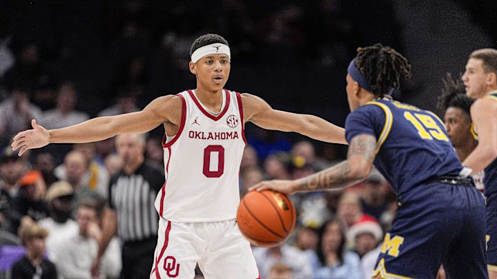 Dec 18, 2024; Charlotte, North Carolina, USA; Oklahoma Sooners guard Jeremiah Fears (0) on defense against Michigan Wolverines guard Rubin Jones (15) during the first half at Spectrum Center. Mandatory Credit: Jim Dedmon-Imagn Images