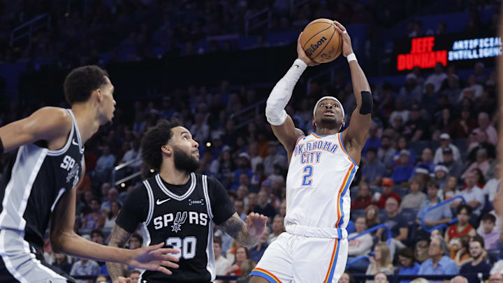 Dec 25, 2025; Oklahoma City, Oklahoma, USA; Oklahoma City Thunder guard Shai Gilgeous-Alexander (2) shoots beside San Antonio Spurs forward Julian Champagnie (30) during the second half at Paycom Center. Mandatory Credit: Alonzo Adams-Imagn Images