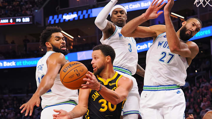 Golden State Warriors guard Stephen Curry (30) passes the ball out between Minnesota Timberwolves center Karl-Anthony Towns (32), forward Jaden McDaniels (3), and center Rudy Gobert (27) during the fourth quarter at Chase Center. Mandatory Credit: Kelley L Cox-Imagn Images