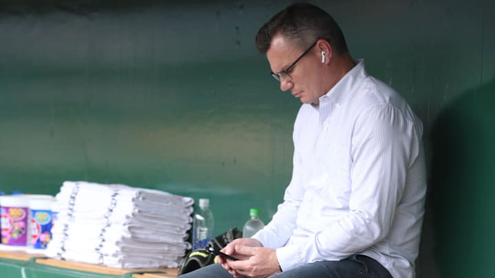 Apr 29, 2025; Pittsburgh, Pennsylvania, USA; Pittsburgh Pirates general manager Ben Cherington checks his phone in he dugout before the game against the Chicago Cubs at PNC Park. Mandatory Credit: Charles LeClaire-Imagn Images