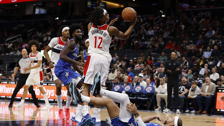 Nov 1, 2025; Washington, District of Columbia, USA; Washington Wizards guard Tre Johnson (12) shoots the ball after colliding with Orlando Magic guard Jalen Suggs (4) in the second half at Capital One Arena. Mandatory Credit: Geoff Burke-Imagn Images