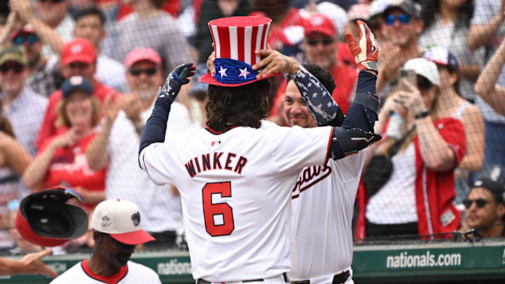 Jul 4, 2024; Washington, District of Columbia, USA; Washington Nationals second baseman Ildemaro Vargas (14) places a patriotic themed top hat on left fielder Jesse Winker (6) after hitting a home run against the New York Mets during the eighth inning at Nationals Park. Mandatory Credit: Rafael Suanes-USA TODAY Sports