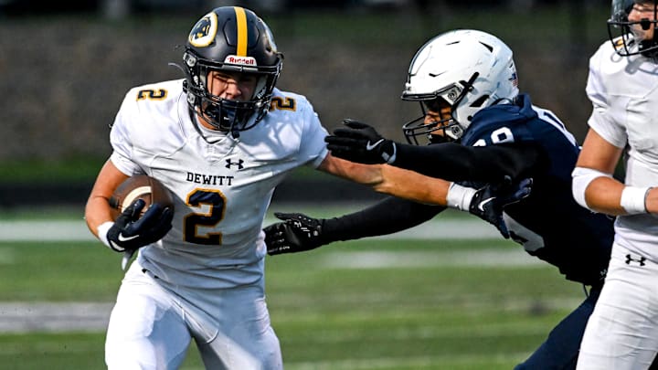 DeWitt's Traverse Moore, left, avoids a tackle attempt by East Lansing's Anthony Green during the first quarter on Friday, Sept. 27, 2024, at East Lansing High School.
