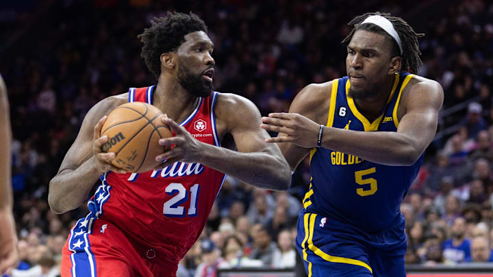 Dec 16, 2022; Philadelphia, Pennsylvania, USA; Philadelphia 76ers center Joel Embiid (21) drives against Golden State Warriors center Kevon Looney (5) during the fourth quarter at Wells Fargo Center. Mandatory Credit: Bill Streicher-Imagn Images