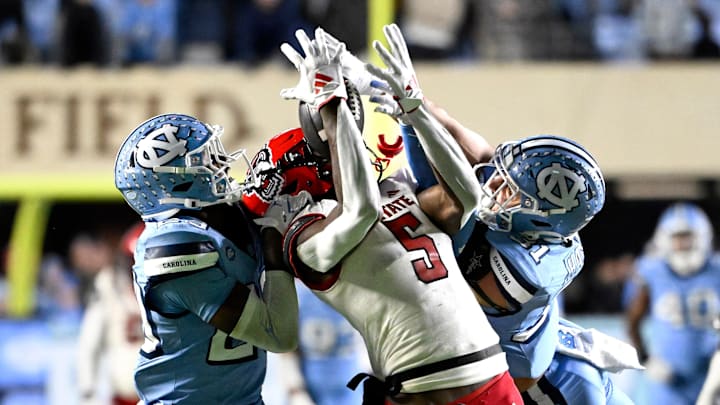 Nov 30, 2024; Chapel Hill, North Carolina, USA; North Carolina State Wolfpack wide receiver Noah Rogers (5) catches a 44 yard pass as North Carolina Tar Heels defensive back Marcus Allen (29) and North Carolina Tar Heels defensive back Will Hardy (31) defend in the fourth quarter at Kenan Memorial Stadium. Mandatory Credit: Bob Donnan-Imagn Images