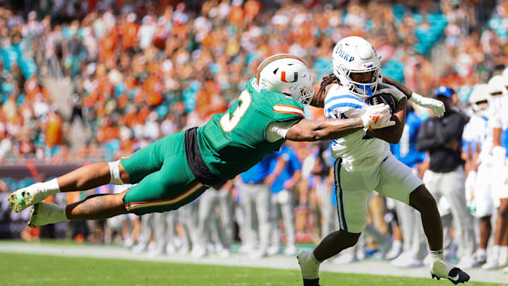 Nov 2, 2024; Miami Gardens, Florida, USA; Duke Blue Devils wide receiver Que'Sean Brown (14) runs with the football past Miami Hurricanes defensive lineman Akheem Mesidor (3) during the second quarter at Hard Rock Stadium. Mandatory Credit: Sam Navarro-Imagn Images