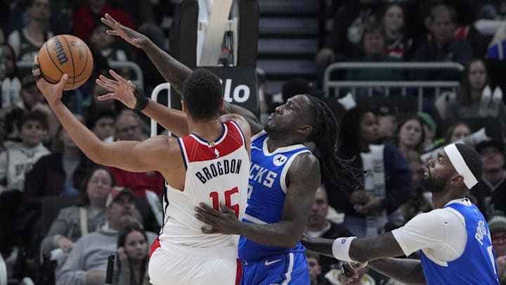 Nov 30, 2024; Milwaukee, Wisconsin, USA; Milwaukee Bucks forward Taurean Prince (12) defends against Washington Wizards guard Malcolm Brogdon (15) while driving to the basket in the first half at Fiserv Forum. Mandatory Credit: Michael McLoone-Imagn Images