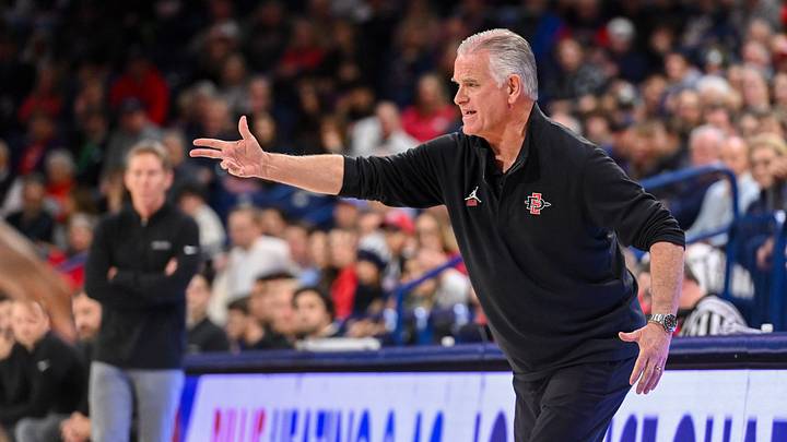 San Diego State head coach Brian Dutcher looks on during a game against Gonzaga at the McCarthey Athletic Center, with Bulldogs head coach Mark Few in the background. San Diego State head coach Brian Dutcher looks on during a game against Gonzaga at the McCarthey Athletic Center, with Bulldogs head coach Mark Few in the background.