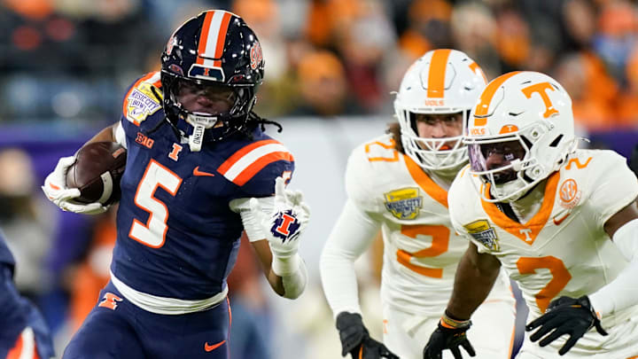 Illinois running back Ca'Lil Valentine (5) runs the ball ahead of Tennessee defensive back Andre Turrentine (2) and linebacker Jadon Perlotte (27) for a first down in the first quarter of the Music City Bowl against Tennessee in an NCAA football game on Dec. 30, 2025, in Nashville, Tennessee.