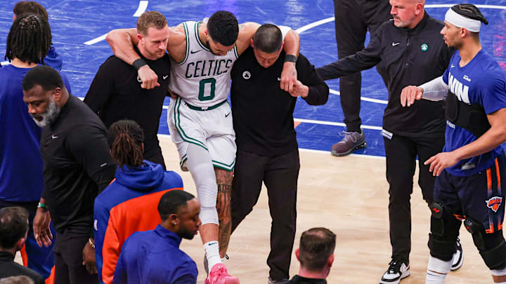 May 12, 2025; New York, New York, USA; Boston Celtics forward Jayson Tatum (0) is helped off the court by after an injury in the second half during game four of the second round for the 2025 NBA Playoffs against the New York Knicks at Madison Square Garden. Tatum would leave the game with an injury after this play. Mandatory Credit: Vincent Carchietta-Imagn Images
