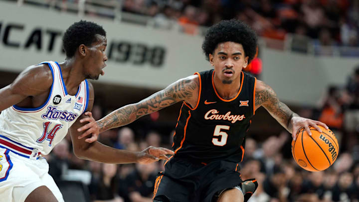 Oklahoma State Cowboys guard Vyctorius Miller (5) dribbles beside Kansas Jayhawks guard Melvin Council Jr. (14) during a men's college basketball game between the Oklahoma State Cowboys and the Kansas Jayhawks at Gallagher-Iba Arena in Stillwater, Okla., Wednesday, Feb. 18, 2026.