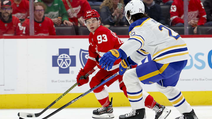 Mar 16, 2024; Detroit, Michigan, USA;  Detroit Red Wings right wing Alex DeBrincat (93) skates with the puck defended by Buffalo Sabres defenseman Owen Power (25) in the second period at Little Caesars Arena. Mandatory Credit: Rick Osentoski-Imagn Images