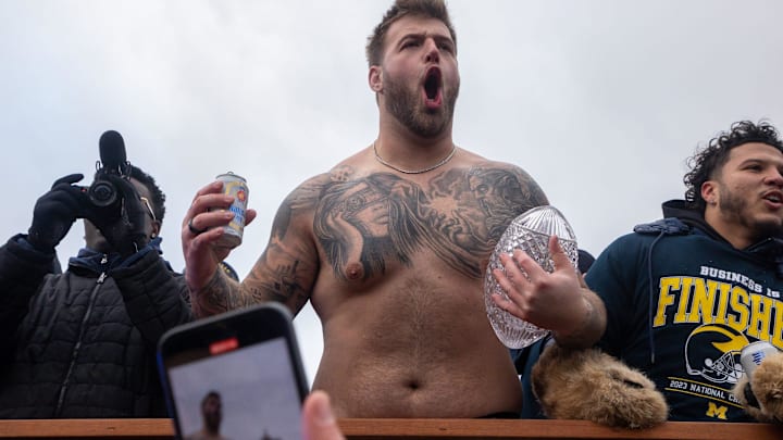 Michigan’s Trevor Keegan holds a beer in one hand and the 2023 National Championship trophy in the other during a parade. Michigan’s Trevor Keegan holds a beer in one hand and the 2023 National Championship trophy in the other during a parade.