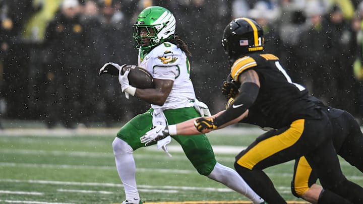 Nov 8, 2025; Iowa City, Iowa, USA; Oregon Ducks running back Noah Whittington (6) runs the ball as Iowa Hawkeyes linebacker Karson Sharar (obscured) and defensive back Xavier Nwankpa (1) attempt to make the tackle during the first quarter at Kinnick Stadium. Mandatory Credit: Jeffrey Becker-Imagn Images