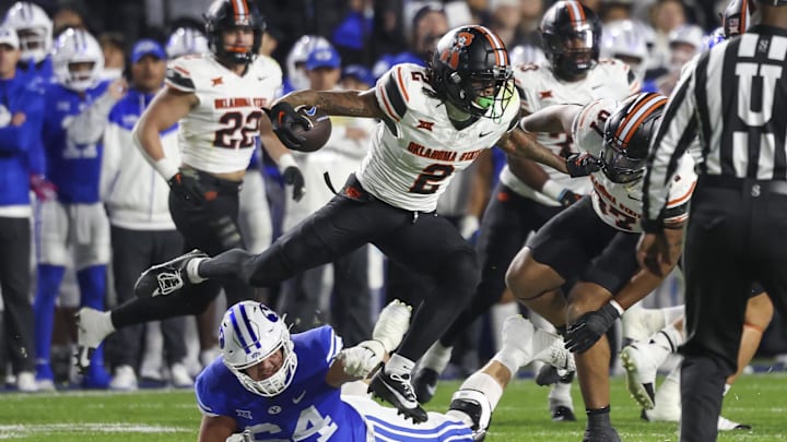 Oct 18, 2024; Provo, Utah, USA; Oklahoma State Cowboys cornerback Korie Black (2) runs after an interception against Brigham Young Cougars offensive lineman Jackson Nelson (54) during the second quarter at LaVell Edwards Stadium. Mandatory Credit: Rob Gray-Imagn Images