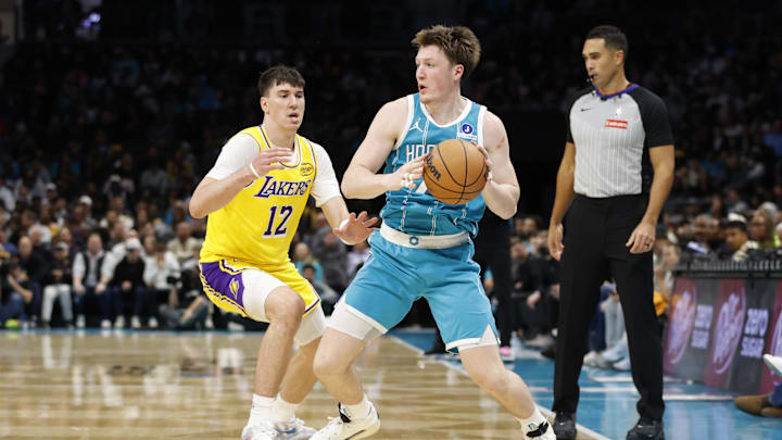 Nov 10, 2025; Charlotte, North Carolina, USA; Charlotte Hornets guard/forward Kon Knueppel (7) is guarded by Los Angeles Lakers forward Jake Laravia (12) during the second half at Spectrum Center. Mandatory Credit: Brian Westerholt-Imagn Images