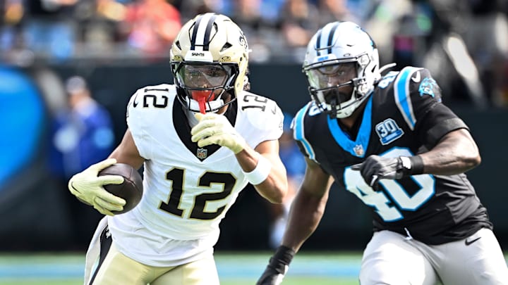 Nov 3, 2024; Charlotte, North Carolina, USA; New Orleans Saints wide receiver Chris Olave (12) with the ball as Carolina Panthers linebacker Charles Harris (40) defends in the first quarter at Bank of America Stadium.