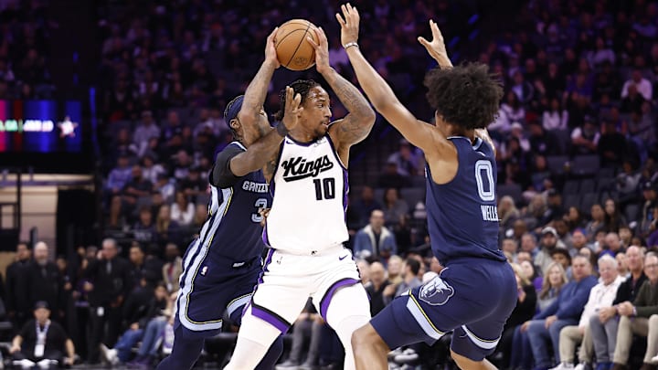 Nov 30, 2025; Sacramento, California, USA; Sacramento Kings forward/guard DeMar DeRozan (10) controls the ball between Memphis Grizzlies guard Kentavious Caldwell-Pope (3) and forward Jaylen Wells (0) during the third quarter at Golden 1 Center. Mandatory Credit: Kelley L Cox-Imagn Images