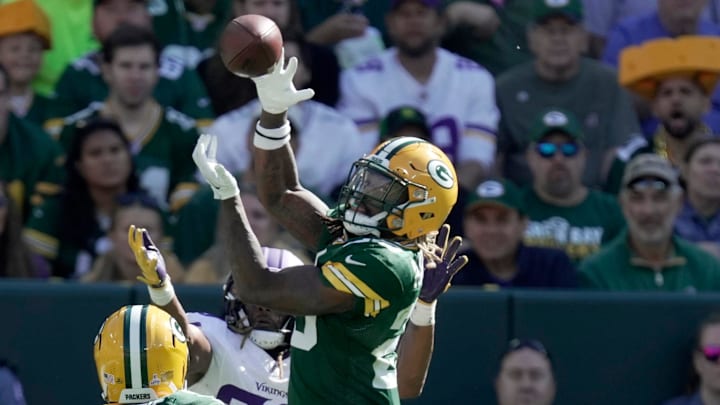 Green Bay Packers safety Xavier McKinney (29) leaps for an interception in front of the Vikings' Aaron Jones.