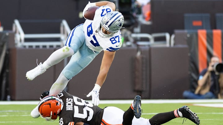 Sep 8, 2024; Cleveland, Ohio, USA; Dallas Cowboys tight end Jake Ferguson (87) falls over Cleveland Browns linebacker Jordan Hicks (58) as he is tackled around his ankle during the third quarter at Huntington Bank Field. Mandatory Credit: Scott Galvin-Imagn Images
