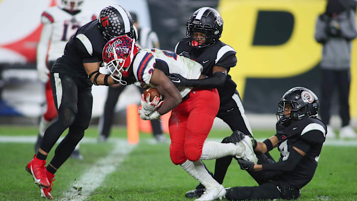 Aliquippa's QaLil Goode (14), Gavin Wilcox (13), and Arison Walker (15) attempt to hold back McKeesport's Kemon Spell (20) from scoring a touchdown during the second half of the WPIAL 4A Championship game Friday evening at Acrisure Stadium in Pittsburgh, PA.