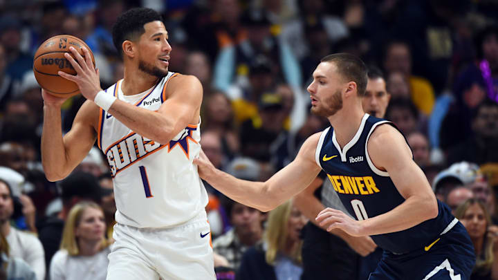 Oct 25, 2025; Denver, Colorado, USA; Phoenix Suns guard Devin Booker (1) is defended by Denver Nuggets guard Christian Braun (0) during the first half at Ball Arena. Mandatory Credit: Christopher Hanewinckel-Imagn Images