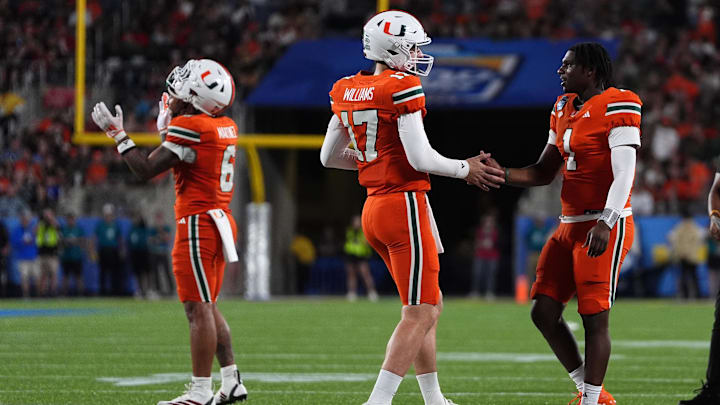 Dec 28, 2024; Orlando, FL, USA; Miami Hurricanes quarterback Emory Williams (17) shakes hands with quarterback Cam Ward (1) after a touchdown against the Iowa State Cyclones during the second half at Camping World Stadium.  