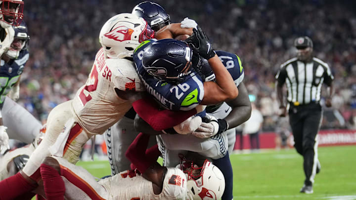 Seattle Seahawks running back Zach Charbonnet (26) breaks into the end zone for a touchdown through Arizona Cardinals safety Jalen Thompson (34) and linebacker Mack Wilson Sr. (2) at State Farm Stadium in Glendale on Sept. 25, 2025.