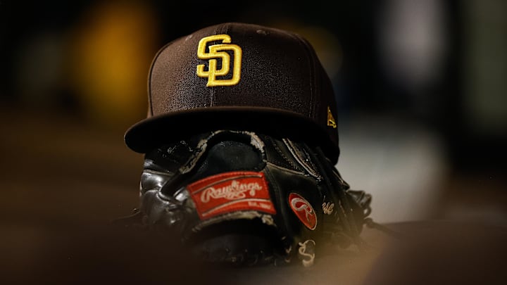 Jun 17, 2022; Denver, Colorado, USA; A detail view of a San Diego Padres hat on a glove in the dugout in the ninth inning against the Colorado Rockies at Coors Field. Mandatory Credit: Isaiah J. Downing-Imagn Images