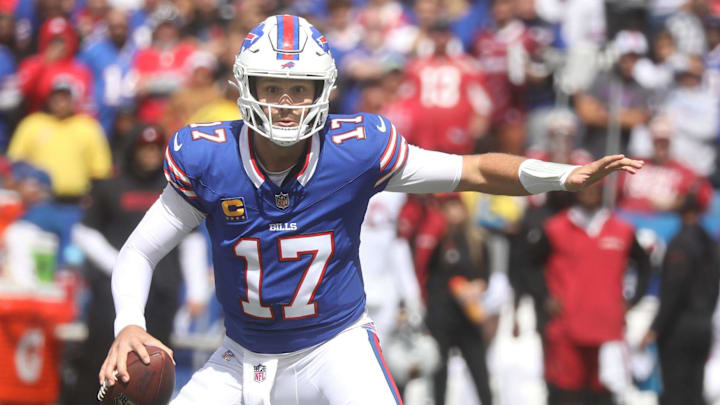 Buffalo Bills quarterback Josh Allen looks to throw a pass while holding off a defender.