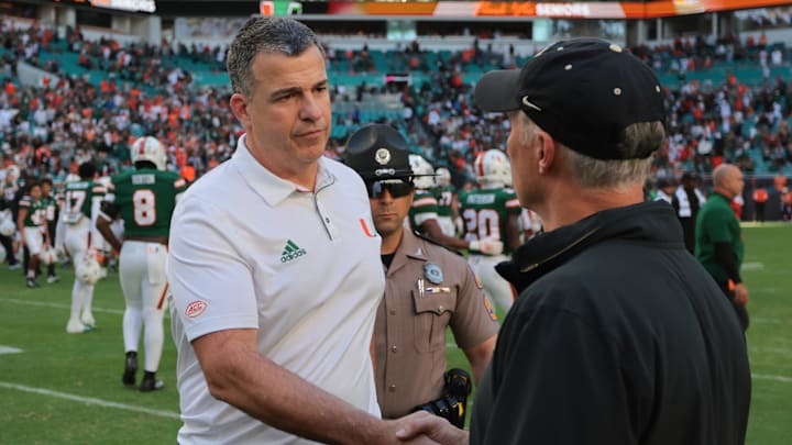 Nov 23, 2024; Miami Gardens, Florida, USA; Miami Hurricanes head coach Mario Cristobal shakes hands with Wake Forest Demon Deacons head coach Dave Clawson after the game at Hard Rock Stadium. Mandatory Credit: Sam Navarro-Imagn Images