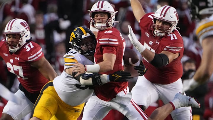 Oct 14, 2023; Madison, Wisconsin, USA; Wisconsin Badgers quarterback Braedyn Locke (18) fumbles the ball after being hit by Iowa Hawkeyes defensive lineman Aaron Graves (95) during the fourth quarter at Camp Randall Stadium. Mandatory Credit: Mark Hoffman-Imagn Images