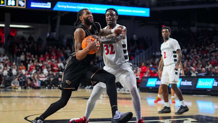Feb 8, 2026; Cincinnati, Ohio, USA;  UCF Knights forward Jordan Burks (99) drives to the basket against Cincinnati Bearcats forward Jalen Celestine (32) in the second half at Fifth Third Arena. Mandatory Credit: Aaron Doster-Imagn Images
