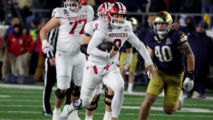 Dec 20, 2024; Notre Dame, Indiana, USA; Indiana Hoosiers quarterback Kurtis Rourke (9) scrambles against Notre Dame Fighting Irish defensive lineman Joshua Burnham (40) during the second half at Notre Dame Stadium. Mandatory Credit: Trevor Ruszkowski-Imagn Images