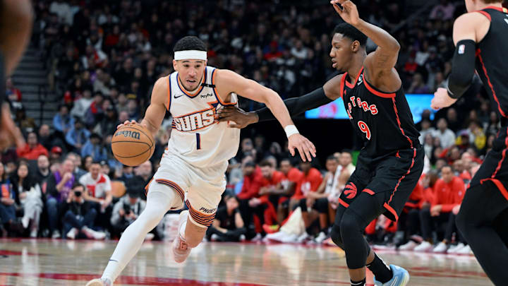Feb 23, 2025; Toronto, Ontario, CAN;  Phoenix Suns guard Devin Booker (1) dribbles the ball past Toronto Raptors forward RJ Barrett (9) in the second half at Scotiabank Arena. Mandatory Credit: Dan Hamilton-Imagn Images