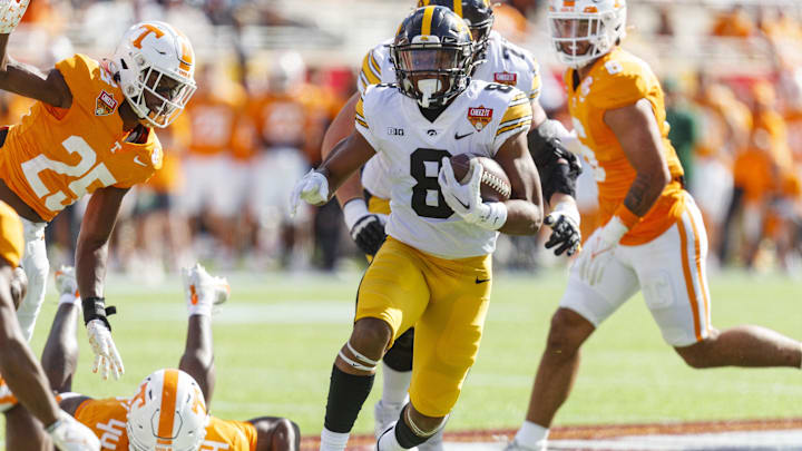 Jan 1, 2024; Orlando, FL, USA; Iowa Hawkeyes running back Terrell Washington Jr. (8) runs the ball past Tennessee Volunteers defensive back Jourdan Thomas (25) and linebacker Elijah Herring (44) during the first quarter at Camping World Stadium. Mandatory Credit: Morgan Tencza-USA TODAY Sports