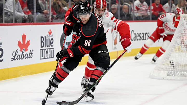 Mar 4, 2025; Detroit, Michigan, USA;  Carolina Hurricanes right wing Mikko Rantanen (96) steers the puck away from Detroit Red Wings defenseman Justin Holl (3) in the first period at Little Caesars Arena. Mandatory Credit: Lon Horwedel-Imagn Images
