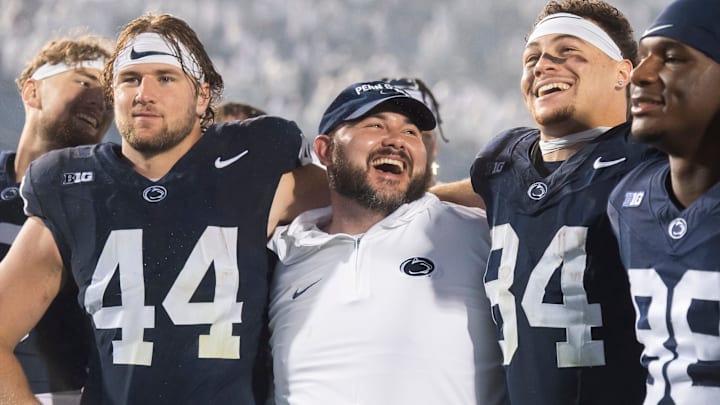 Penn State co-offensive coordinator/tight ends coach Ty Howle (center) puts his arms around tight ends Tyler Warren (44) and Theo Johnson (84)