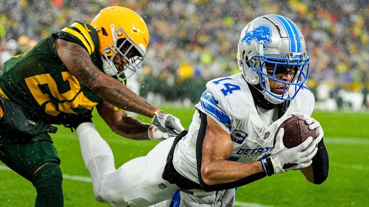 Detroit Lions wide receiver Amon-Ra St. Brown (14) catches a pass in front of Green Bay Packers cornerback Keisean Nixon to start the second quarter at Lambeau Field.